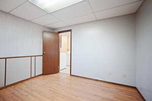 Spare room with a drop ceiling and light hardwood / wood-style flooring