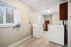 Laundry area with light hardwood / wood-style floors, cabinets, and washing machine and clothes dryer