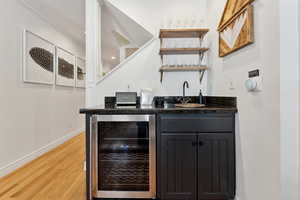 Bar featuring wine cooler, sink, and light hardwood / wood-style flooring