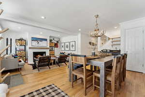 Dining space featuring a notable chandelier, ornamental molding, sink, and light wood-type flooring