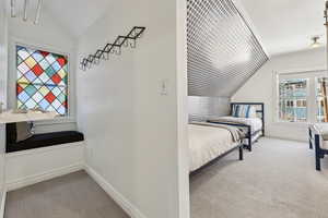 Bedroom featuring light colored carpet and vaulted ceiling