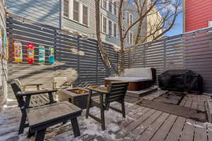 Wooden deck with area for grilling, a hot tub, and a fire pit