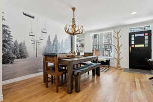 Dining room with an inviting chandelier, light hardwood / wood-style flooring, and ornamental molding