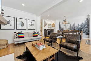 Living room featuring a notable chandelier, crown molding, and light hardwood / wood-style floors