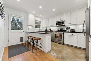 Kitchen featuring a breakfast bar area, stainless steel appliances, a center island, tasteful backsplash, and white cabinets