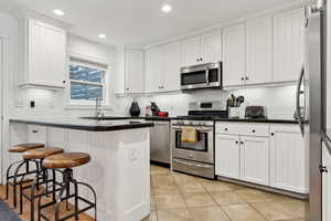 Kitchen featuring sink, a breakfast bar area, stainless steel appliances, and white cabinets