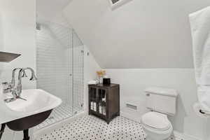 Bathroom featuring toilet, vaulted ceiling, sink, and a shower with shower door