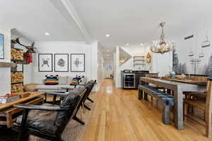 Living room featuring bar, crown molding, an inviting chandelier, beverage cooler, and light hardwood / wood-style floors