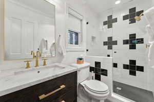 Bathroom with vanity, a tile shower, and toilet