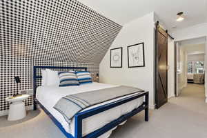 Bedroom featuring crown molding, light colored carpet, and a barn door