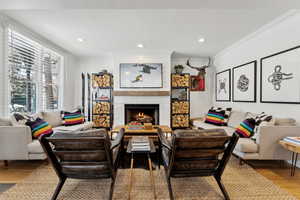 Living room with crown molding, hardwood / wood-style flooring, and a large fireplace