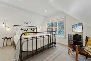 Carpeted bedroom featuring vaulted ceiling