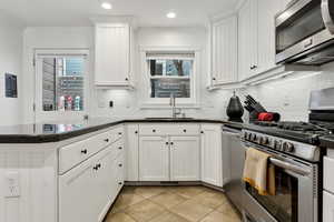 Kitchen with sink, white cabinetry, stainless steel appliances, decorative backsplash, and kitchen peninsula