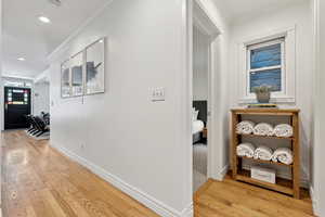 Hall with ornamental molding and light hardwood / wood-style flooring