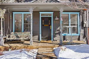 Snow covered property entrance with a porch