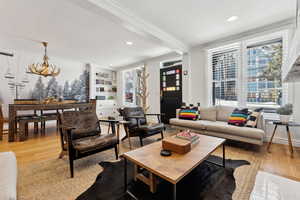 Living room with crown molding, light hardwood / wood-style floors, and a chandelier