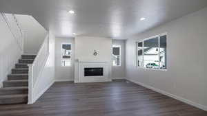 Unfurnished living room featuring a tiled fireplace, dark wood-type flooring, and a textured ceiling