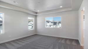 Carpeted empty room with a raised ceiling and a textured ceiling