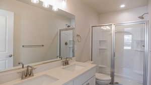 Bathroom with vanity, a shower with shower door, and toilet