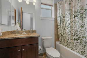 Full bathroom with vanity, shower / tub combo with curtain, and toilet