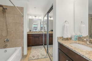 Bathroom with tiled shower / bath combo, vanity, and tile patterned flooring