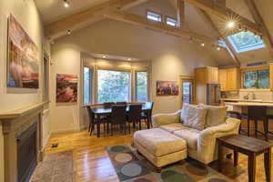 Living room featuring a tiled fireplace, a skylight, light hardwood / wood-style flooring, and a wealth of natural light