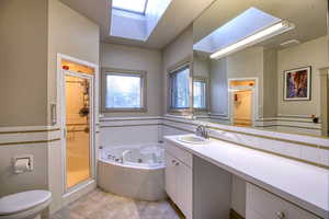 Full bathroom with tile walls, a skylight, separate shower and tub, tile patterned floors, and toilet