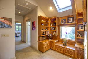 Office area featuring lofted ceiling with skylight and light colored carpet