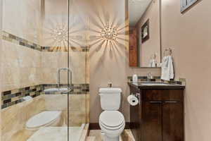 Bathroom featuring walk in shower, vanity, and toilet