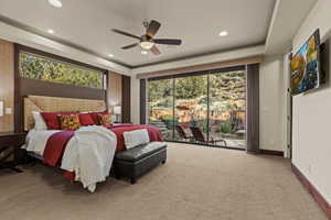 Carpeted bedroom with a raised ceiling, access to exterior, and ceiling fan