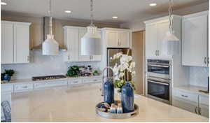 Kitchen with gas cooktop, double oven, hanging light fixtures, tasteful backsplash, and white cabinets