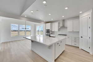 Kitchen with gas stovetop, a sink, recessed lighting, wall chimney exhaust hood, and oven