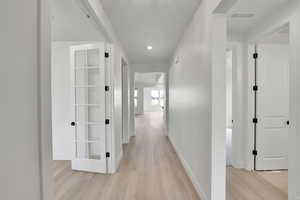 Corridor featuring baseboards, recessed lighting, light wood-style flooring, and visible vents