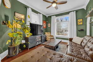 Living room with hardwood / wood-style flooring, ornamental molding, and a healthy amount of sunlight