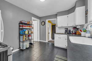 Kitchen featuring white cabinetry, sink, and decorative backsplash