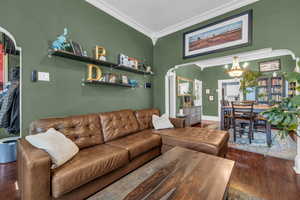 Living room featuring ornamental molding, dark hardwood / wood-style floors, and a chandelier