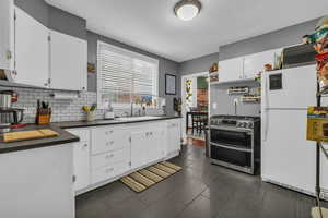 Kitchen with double oven range, sink, white fridge, and white cabinets