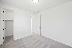 Unfurnished bedroom with a closet, a spacious closet, and light carpet