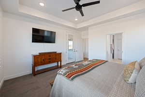 Bedroom with access to exterior, a tray ceiling, carpet floors, and ceiling fan