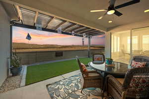 Patio terrace at dusk with ceiling fan, a pergola, and a lawn