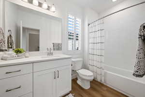 Full bathroom featuring shower / bath combination with curtain, vanity, toilet, and hardwood / wood-style floors