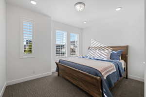 Bedroom with dark carpet and multiple windows