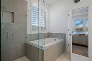 Bathroom with tile patterned flooring, a wealth of natural light, and independent shower and bath