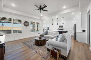 Living room featuring a raised ceiling, hardwood / wood-style flooring, and ceiling fan