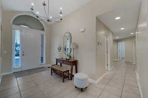 Entryway with lofted ceiling, light tile patterned floors, and a chandelier