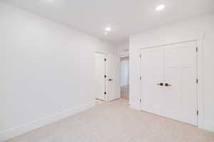 Unfurnished bedroom with light colored carpet and a closet