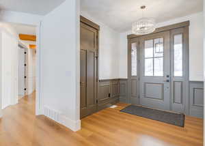 Foyer entrance with hardwood / wood-style floors and a chandelier