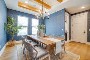 Dining space featuring a tray ceiling, a notable chandelier, and light hardwood / wood-style flooring