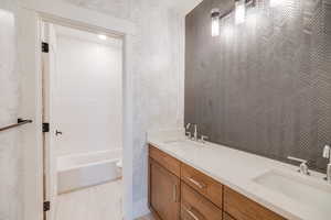 Full bathroom with tiled shower / bath combo, vanity, and toilet