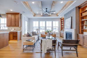 Living room featuring sink, ceiling fan, a large fireplace, built in shelves, and light wood-type flooring